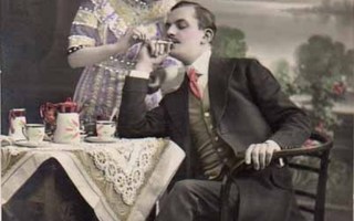 RAKKAUS / Tyttö sytyttää istuvan miehen sikarin. 1900-l.