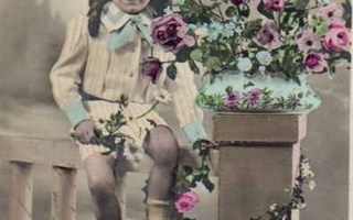 LAPSI / Hymyilevä lapsi aidalla - kukka-asetelma. 1900-l.